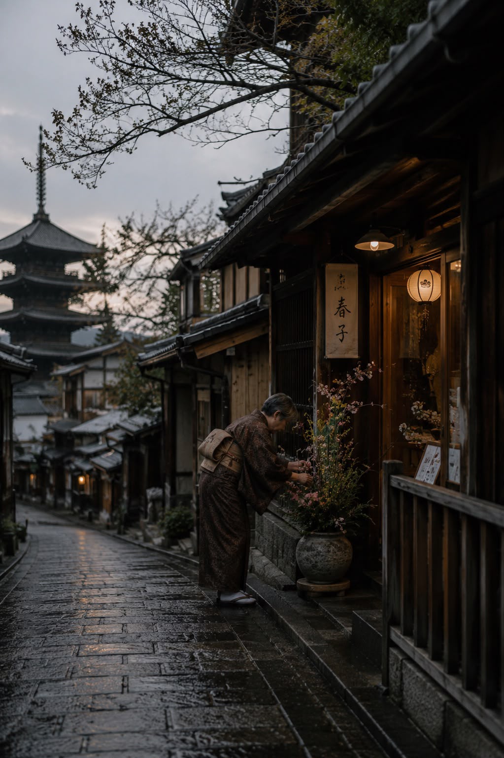 Una mujer en kimono arregla flores al amanecer, con la pagoda Yasaka al fondo